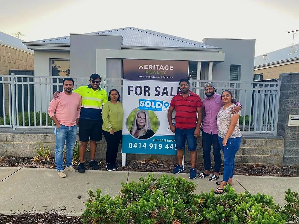 Happy clients with sold sign after Harrisdale home sale